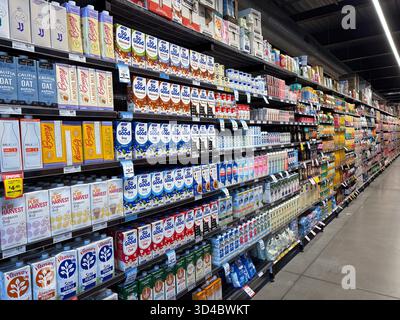 Supermarket aisle displaying a wide selection of plant-based milks like almond, soy, and oat beverages, along with other drinks in a modern grocery st Stock Photo