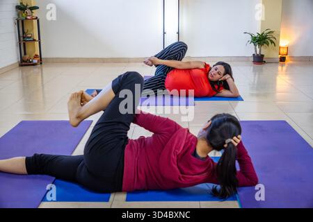 Women performing relaxing yoga stretches on mats during a wellness class Stock Photo