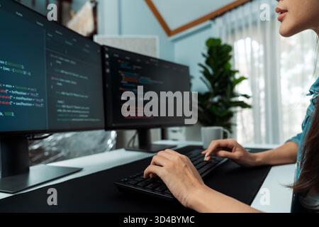 Young Asian in IT developer creating with typing online information on pc with coding program data of website application, wearing jeans shirt Stock Photo