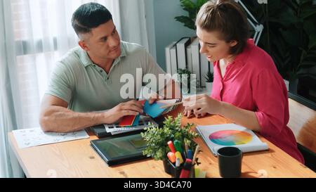 Professional happy interior designer looking at tablet while project manager choosing color palettes. Top view of smart graphic designing and looking Stock Photo