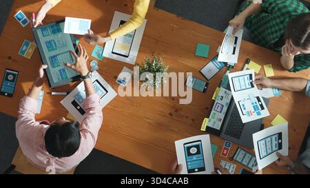 Team working at Ux Ui design for mobile phone interface while manager hand out document about wireframe prototype. Top view of project manager explain Stock Photo