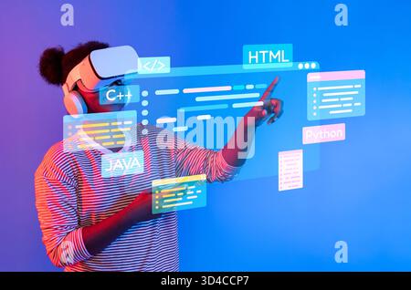 A young person explores programming concepts through virtual reality, showcasing various coding languages on a vibrant digital interface in a modern Stock Photo