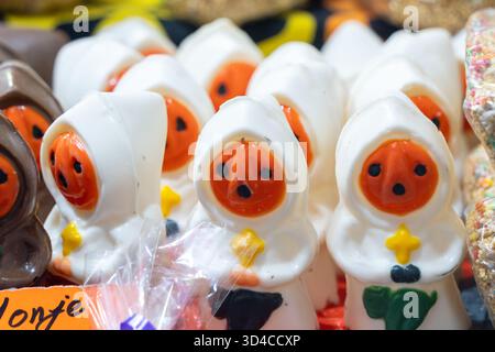 A bunch of Halloween-themed figures are on display in a store. They are all white and orange. Mexican Day of the Dead tradition, offerings, food, colo Stock Photo