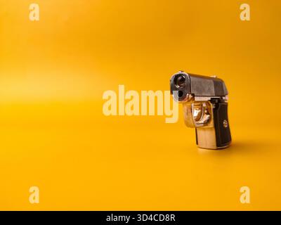 A small handgun is on a yellow background with copy and text space. Stock Photo