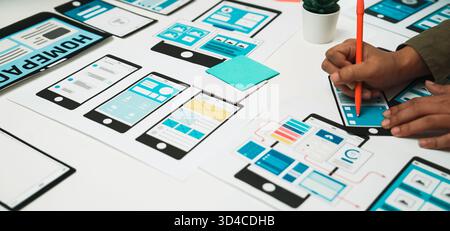 A person sketches a digital interface on paper mockups using colorful stationery, showcasing the creative process in user experience design and Stock Photo