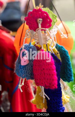A colorful assortment of knitted items, including a skeleton, are hanging from a string. Mexican Day of the Dead tradition, offerings, food, colors, d Stock Photo