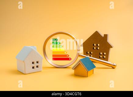 Energy efficiency rating concept with colorful scale A to G focused in magnifying glass lens and different house models, symbolizing home energy inspe Stock Photo