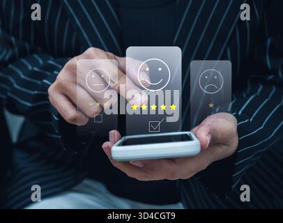 Close-up hand giving five-star rating on smartphone with satisfaction icons, representing user feedback, customer experience, mobile review system, an Stock Photo