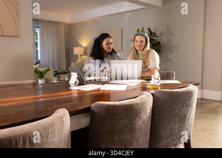 Collaborating Diverse female colleagues working on laptop at dining workspace, with documents Stock Photo