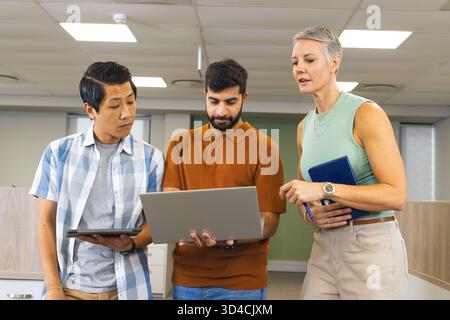 Collaborating Diverse coworkers discussing project in modern office, with silver laptop and tablet Stock Photo