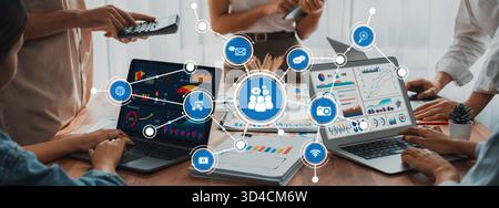 A dynamic workplace scene featuring diverse professionals collaborating with laptops and digital media, highlighting teamwork and communication in Stock Photo