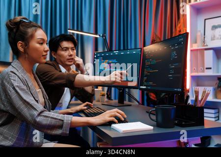 IT developers discussing with point to intelligent website development coder system running data online two screens information technology at neon Stock Photo