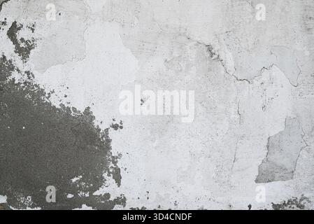 Close-up of aged plaster wall with chipped paint and gray cement texture. Stock Photo