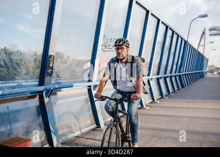 Male cyclist riding bike down the street. Stock Photo