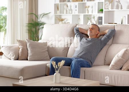 Relaxed senior man resting alone sitting on a couch at home Stock Photo