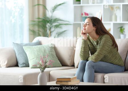 Relaxed woman in green resting on a couch at home Stock Photo