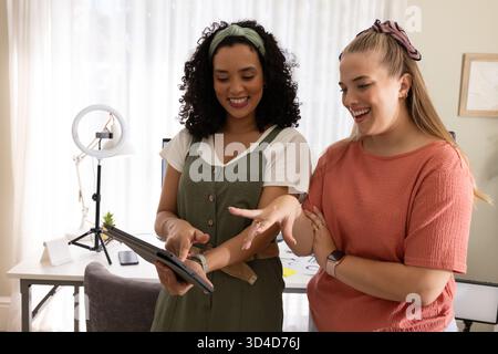 Collaborating Diverse female colleagues using digital tablet in home office, with ring light Stock Photo