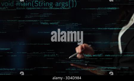 A close-up of hands holding a tablet with dynamic computer code displayed on the screen. This abstract image represents modern technology and software Stock Photo