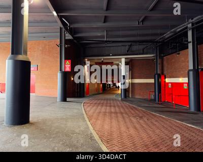 Manchester, UK - September 30, 2025: Urban indoor scene in Manchester car park featuring brick walls, red doors, and a curved brick walkway. Stock Photo