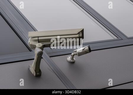 Security surveillance cameras mounted on a modern building wall for observation and protection. Stock Photo