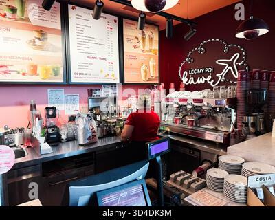 Nowy Dwor Mazowiecki, Poland - October 22, 2025: A barista works behind a vibrant cafe counter with espresso machines and a menu in a Polish coffee sh Stock Photo