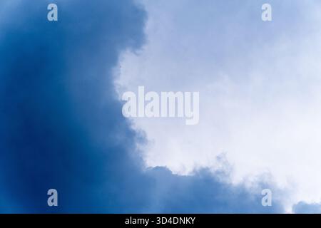 A close-up view of dark, heavy storm clouds in the sky. The moody, dramatic blue and white clouds create an ominous and abstract weather background. Stock Photo