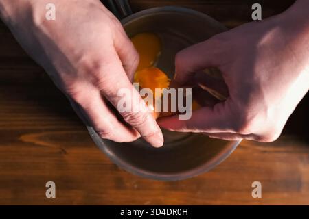 Breaking eggs in a pot, raw eggs for beating. Stock Photo