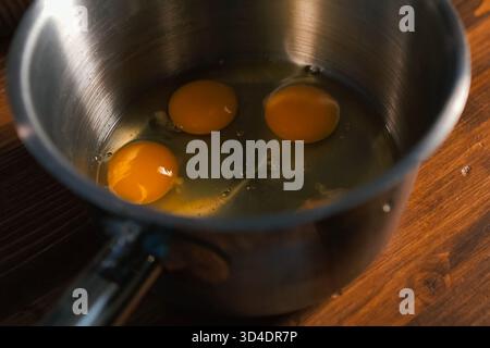 Breaking eggs in a pot, raw eggs for beating. Stock Photo