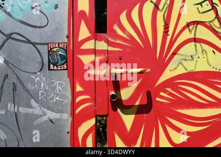 Metal Security Door or Entrance Decorated in Modernist Abstract Graffiti with Colourful Red and Yellow Door Handle Stock Photo