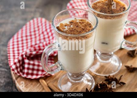 Eggnog with Cinnamon and Christmas Decorations on wooden table Stock Photo