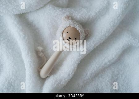Close, well-lit view of a wooden baby toy resting on plush cloth, timeless, safe and soothing imagery for newborn collections Stock Photo