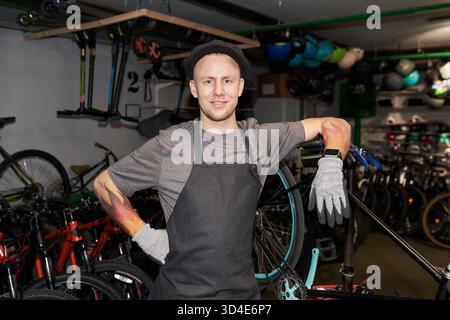 Portrait of Young Man Smiling While Working in Bicycle Workshop Stock Photo