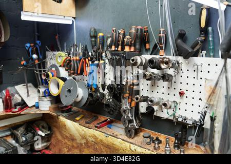 Assorted Bicycle Repair Tools and Parts Hanging on Workshop Wall Pegboard Stock Photo