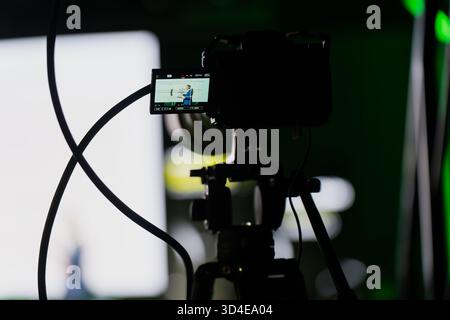 Behind the scenes view of camera display showing presenter in focus while recording stage event, artistic representation of professional filming, tech Stock Photo