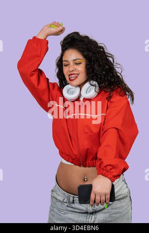 Cheerful woman with curly hair enjoying music, showing joy and carefree lifestyle Stock Photo