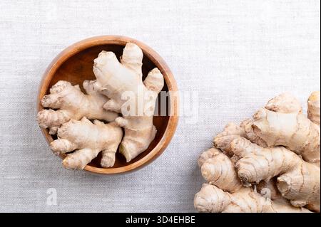 Fresh ginger root, in a wooden bowl, on linen. Rhizomes of Zingiber officinale, used in cooking for its flavor, and in traditional folk medicine. Stock Photo