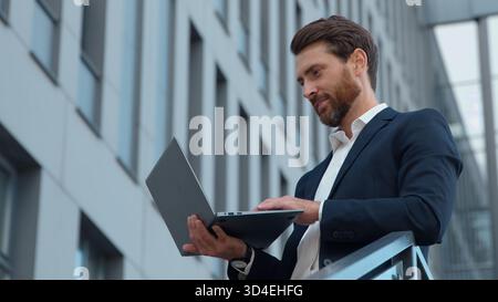 Concentrated Caucasian mature business man typing laptop in city pensive middle-aged professional businessman male worker with wireless PC working Stock Photo