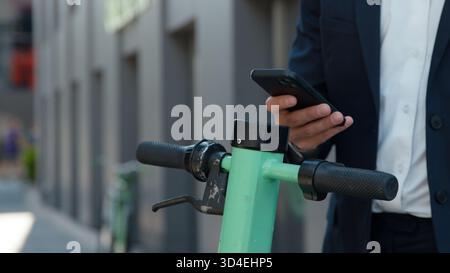 Unrecognizable business man using mobile phone app to rent electric scooter in city unknown businessman male paying with smartphone renting driving Stock Photo
