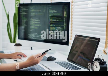 Programming developing software application. programmer writing program code with two monitors and working hacker on a new software. || Model released Stock Photo