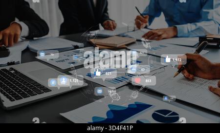 A diverse business team engages in discussion over financial reports while utilizing modern technology, reflecting collaboration and social media Stock Photo