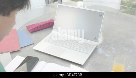 Displaying open white laptop showing blank screen on round glass table, with phone and notebooks Stock Photo