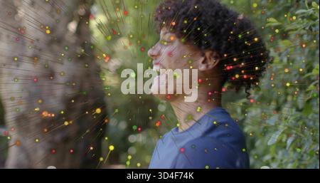 Smiling man wearing blue t-shirt standing in garden, showing earring and multicolored overlay Stock Photo
