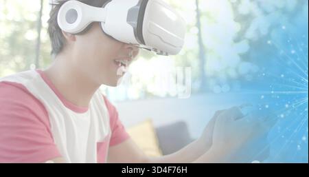 Using white VR headset with headphones, man wearing pink sleeves T-shirt on couch with blue overlay Stock Photo