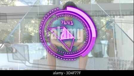 Asian man wearing teal tee sitting on concrete steps in atrium, with purple HUD overlay Stock Photo