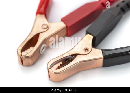 A close up of two alligator clips with red and black handles on white background, used for electrical connections. metal clamps are open Stock Photo
