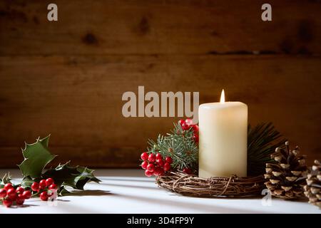 White candle with natural holly berries Stock Photo