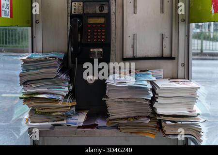 Vienna, Austria - October 4, 2025 - Old telephone booth filled with stacks of newspapers. Stock Photo
