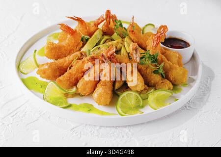 Food, Golden fried shrimp served with slices of fresh lime and dipping sauce, garnished with herbs Stock Photo