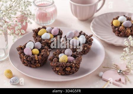 Food, Easter chocolate rice nest cake with mini candy eggs, creative recipe for Easter table. Pink background Stock Photo
