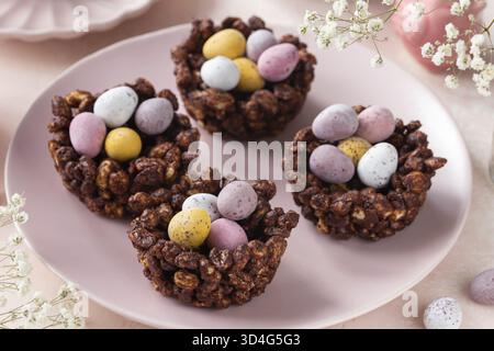 Food, Sweet and tasty Easter chocolate rice nest cake with mini candy eggs, creative recipe for Easter table. Pink background Stock Photo